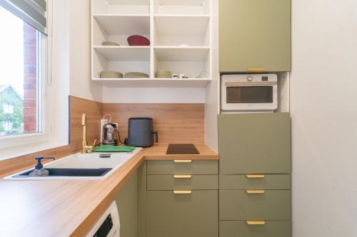 - une cuisine avec des placards verts et blancs et un évier dans l'établissement Arau casa - Appt à Sannois avec jardin, à Sannois