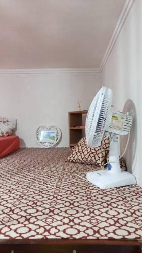 a bedroom with a white fan on a bed at Kitnet MiniHouse do Alto in Lençóis