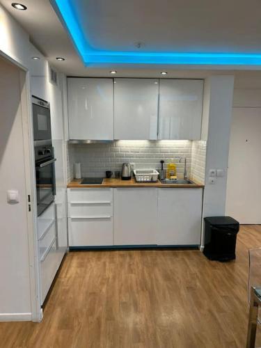 une cuisine avec des placards blancs et un plafond bleu dans l'établissement logement moderne ambiance led personnalisable, à Stains