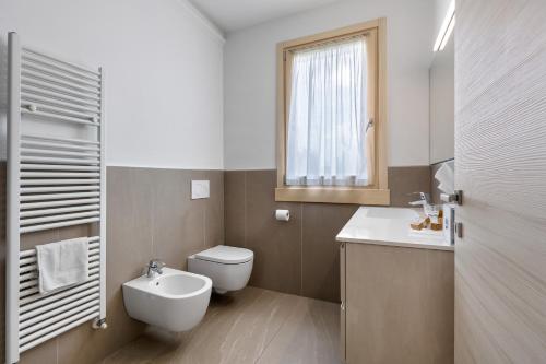 Un baño con inodoro, lavabo y ventana. en Agriturismo Le Campagnole Pink, en Bardolino