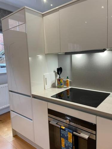 a kitchen with white cabinets and a stove top oven at Charming & Cosy Town Centre Home with Parking in Guildford