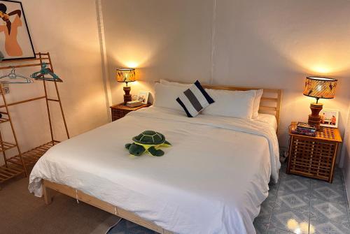 une chambre avec un lit blanc avec une tortue en peluche dessus dans l'établissement Coral Cottage Beach House @ Phang Nga, à Thai Muang
