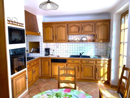 a kitchen with wooden cabinets and a table and a chair at Melabelle in Malandry