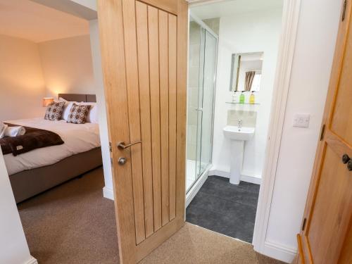 une chambre avec un lit et une porte menant à une salle de bain dans l'établissement Holborn Cottage, Blencathra Street, à Keswick