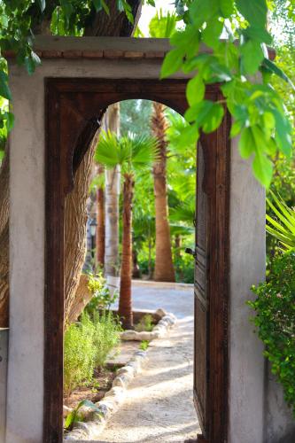 an entrance to a garden with a wooden door at Weedan Hôtel&Spa Marrakech in Oulad Snaguia