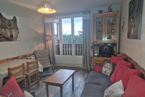 a living room with a couch and a table at Appartement familial au Revard Vue imprenable et accès direct aux pistes in Montcel