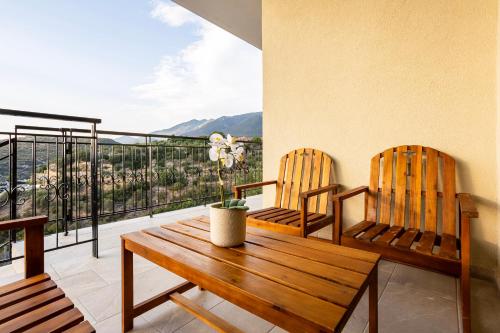 a balcony with two wooden chairs and a wooden table at Martinia Pool Getaways - Majestic Panoramic Views in Áno Ámfia