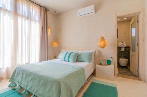 エッサウィラにあるVilla de charme avec piscine chauffée et servicesのベッドルーム1室(青と緑の枕が備わるベッド1台付)
