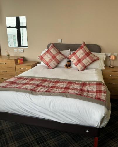 a teddy bear sitting on a bed with pillows at Britannia Inn Glasgow in Glasgow