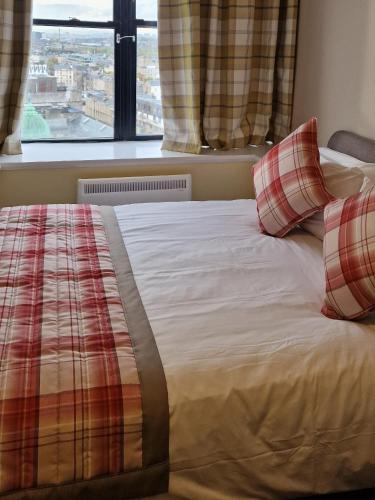 a bed with red and white pillows and a window at Britannia Inn Glasgow in Glasgow