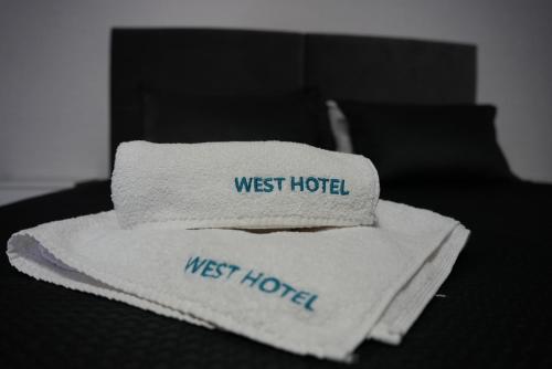 a stack of towels sitting on top of a bed at West Hotel in Mostiska