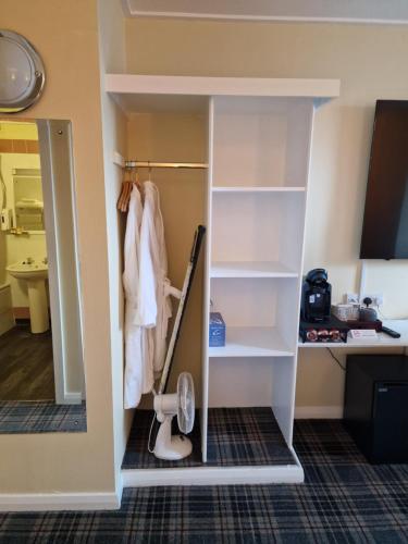 a walk in closet with white shelves and a mirror at Britannia Inn Glasgow in Glasgow