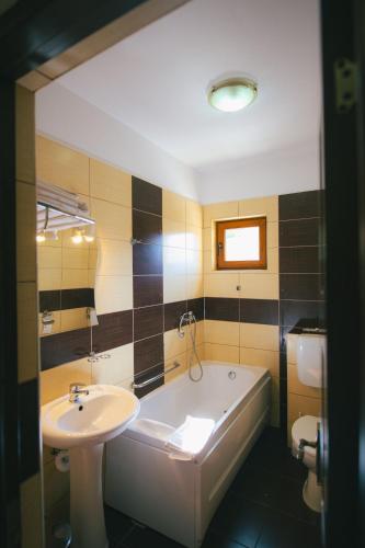 a bathroom with a tub and a sink and a toilet at Del Monte Predeal in Predeal