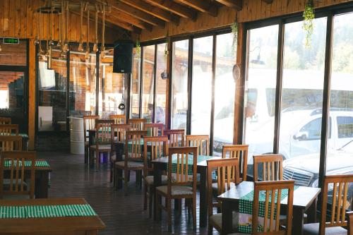 a restaurant with wooden tables and chairs and windows at Del Monte Predeal in Predeal