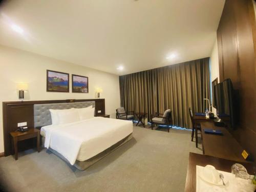 a hotel room with a bed and a television at Peace Hotel Hạ Long in Ha Long