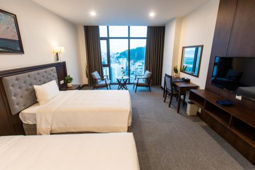 a hotel room with two beds and a flat screen tv at Peace Hotel Hạ Long in Ha Long