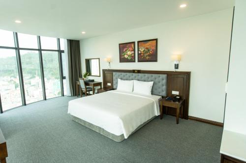 a bedroom with a large white bed and a desk at Peace Hotel Hạ Long in Ha Long