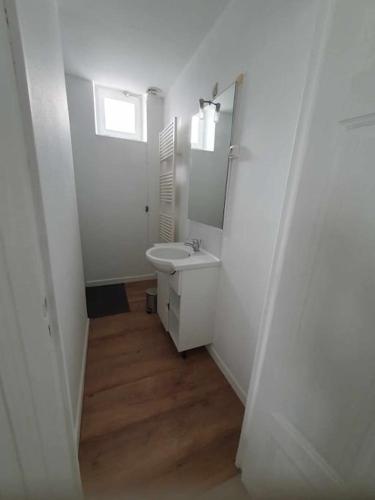 a white bathroom with a sink and a mirror at Gîte de l'ancienne gare in Bussière-Dunoise