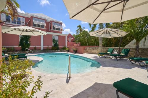 una piscina con due ombrelloni e una casa di Royal Palms Hotel a Hamilton