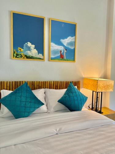 a bed with blue pillows and two pictures on the wall at Cuckoo's Nest Ao Nang in Ban Khlong Son