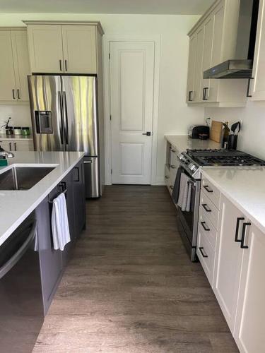 a kitchen with a sink and a refrigerator at Spacious 3 Bdrm Retreat, Muskoka Room & Fireplace in Bracebridge