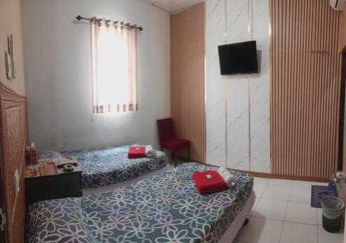 a hotel room with two beds and a television at BOTANIA HOMESTAY BATAM in Nongsa