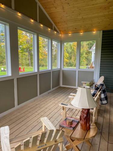 a screened in porch with chairs and a lamp at Spacious 3 Bdrm Retreat, Muskoka Room & Fireplace in Bracebridge