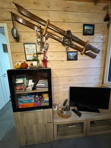 a living room with a tv and a wooden wall at Le Chalet du Bonheur à Soucht in Soucht