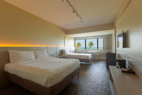 a hotel room with a large bed and a table at Ritz Lagoa da Anta Hotel & SPA in Maceió