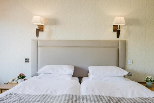 two beds in a hotel room with white sheets and pillows at Winchester Royal Hotel in Winchester