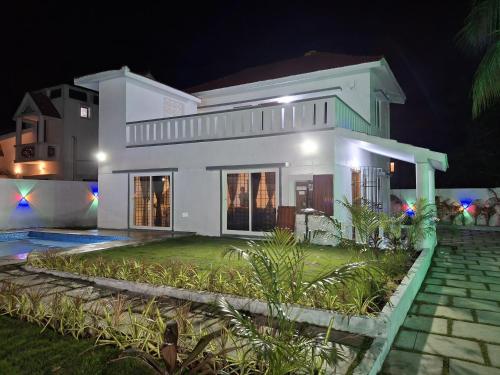a white house at night with a yard at Vasantham Villas ECR 3BHK in Tirupporūr