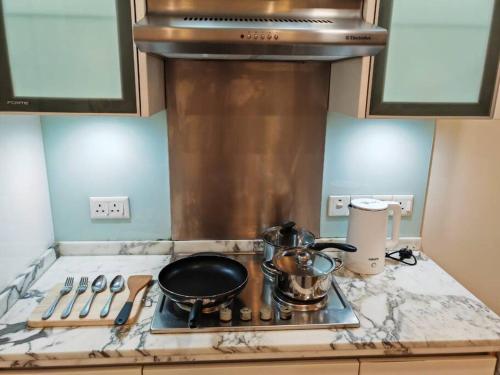 a kitchen counter with a stove with a pot on it at Sweet Cozy Marina Suite at Straits Quay in Tanjong Tokong