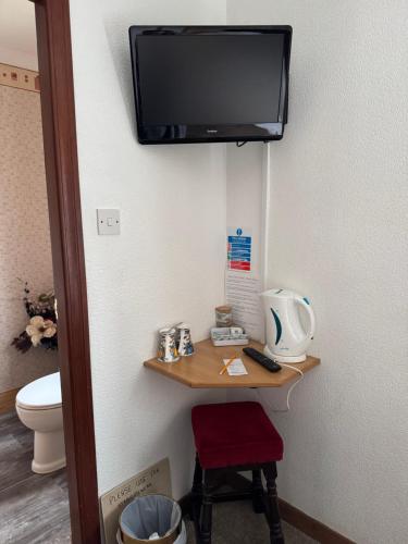 a room with a toilet and a television on the wall at Prince Charlie's Cottage in Gretna Green
