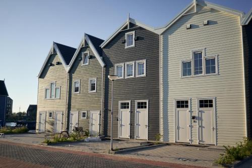 a large wooden building with white doors on a street at Captains Boathouse in Harderwijk