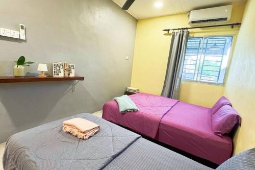 a bedroom with a purple bed and a window at Bercham 81 Homestay in Ipoh