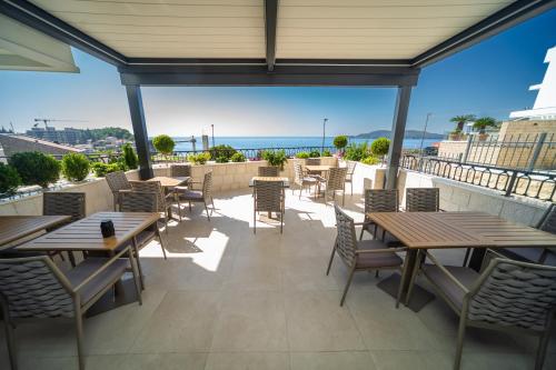 a patio with tables and chairs and the ocean at Exclusive Hotel in Budva