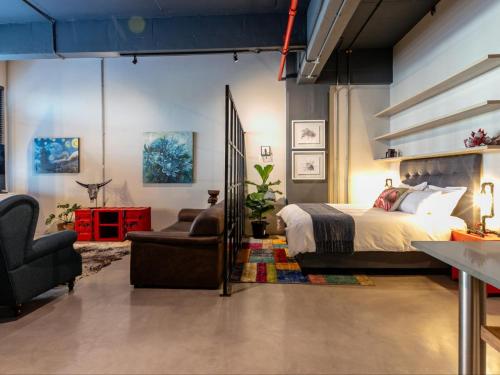 a bedroom with a bed and a couch and a chair at 105 Queens Park in Cape Town