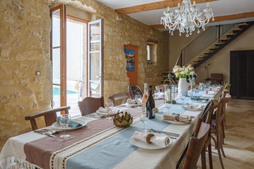 a dining room with a long table with chairs and a chandelier at Maison Flamant in Saint-Geniès-de-Fontedit