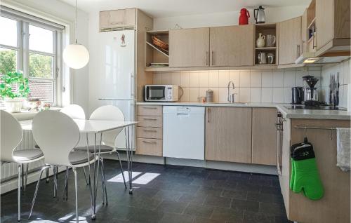 a kitchen with white appliances and a table and chairs at 3 Bedroom Gorgeous Home In Allinge in Allinge