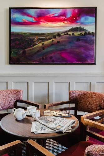 a table and chairs with a painting on the wall at Winchester Royal Hotel in Winchester
