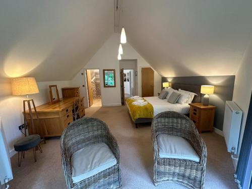 a bedroom with a bed and two chairs at Trewhiddle Retreat V17 by Together Travel - Luxury 4-Bedroom Villa in St Austell