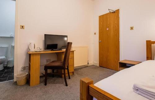 a bedroom with a desk with a television and a bed at The Ben Mhor Hotel, Bar & Restaurant in Grantown on Spey