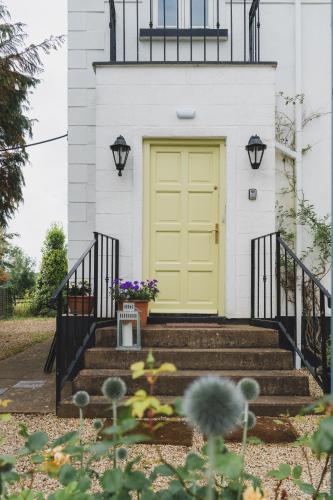 a yellow door on a white house with stairs at Ballyknocken Milking Parlour Self Catering Apartment in Coolnakilly