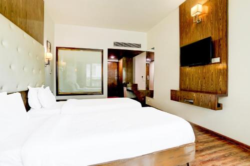 a hotel room with two beds and a television at Palette River Front Railway Station Formerly Host Inn in Ahmedabad