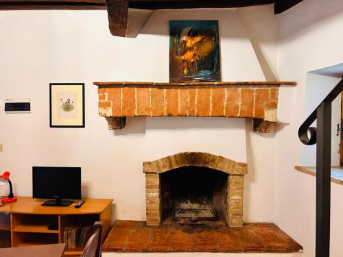 a room with a fireplace with a desk and a computer at Casa Nerina in Castiglione dʼOrcia