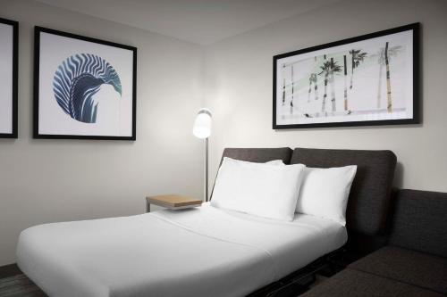 a white bed in a room with two pictures on the wall at Hilton Garden Inn Jacksonville Downtown Southbank in Jacksonville