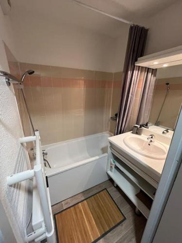 une salle de bain avec une baignoire blanche et un lavabo dans l'établissement Appartement au pied des pistes, à Saint-François-Longchamp