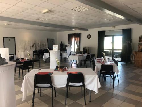 une salle à manger avec des tables blanches et des chaises noires dans l'établissement Love SPA, à Oye-Plage