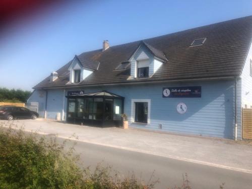 Un bâtiment bleu avec une voiture garée devant. dans l'établissement Love SPA, à Oye-Plage