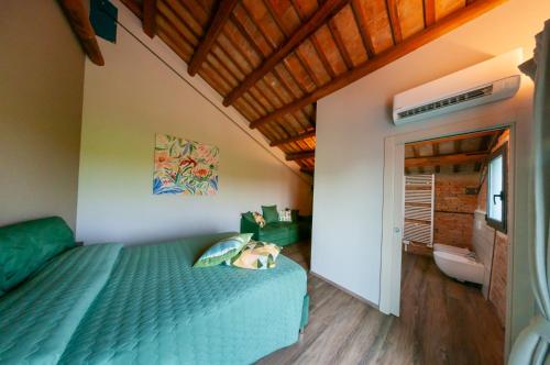 a bedroom with a green bed and a bathroom at Agriturismo PERKE nel Delta del Po in Ariano nel Polesine
